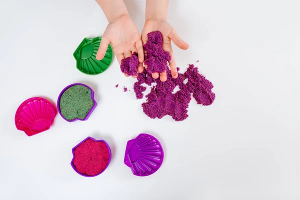 Colorful kinetic sand, plastic molds for sand. Child sculpts and plays with sand. Top view. White background