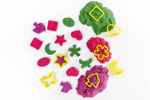 Colorful kinetic sand, plastic molds for sand. Child sculpts and plays with sand. Top view. White background