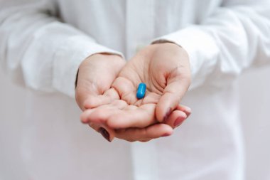 Mavi haplı, vitaminli, kapsüllü kadın eli. Sağlık sigortası, tıbbi tedavi konsepti. Hastalık, hastalıklı tedavi, soğuk sezon konsepti. Yakın çekim görünümü