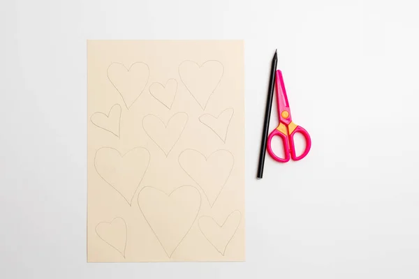 How to make cute paper heart for Valentines day. Children art project. Step by step photo instruction. Step 1. Draw hearts on paper with a pencil