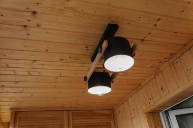 Interior details,ceiling. Stylish scandinavian composition of black bra and wooden walls. Loft style in modern home decor.