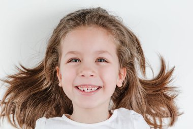 Happy smiling child portrait on the white background. Little todler attractive lovely curious cheerful girl laughs with her white teeth showing.