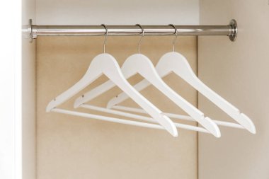 White empty wardrobe closet with hangers. Wooden white hangers on a rod. Store, sale, advertisement concept.