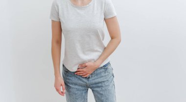 A young woman holds on to her stomach in pain. Digestive problems, gastrointestinal diseases concept. White backgroung.