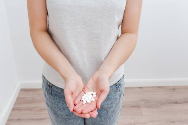 Handful of pills in women hands. White background. Minimalist style