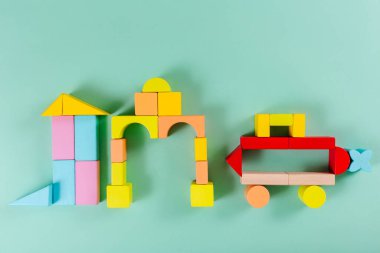 Renkli çocuk ahşap inşaat seti. Kale figürleri ve araba. Turkuaz arka plan. Düz yatıyordu. Doğal malzemeler. Öğrenim ve eğitim kavramı.