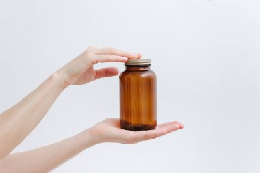 Elinde kapağı olan boş bir cam şişe. Mokup, beyaz arka plan. Alternatif ve bitkisel ilaç tedavisi.