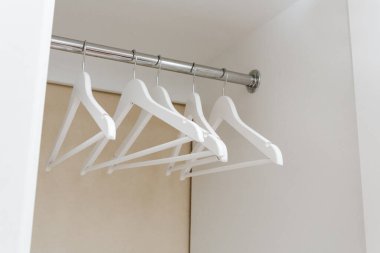 White empty wardrobe closet with hangers. Wooden white hangers on a rod. Store, sale, advertisement concept.