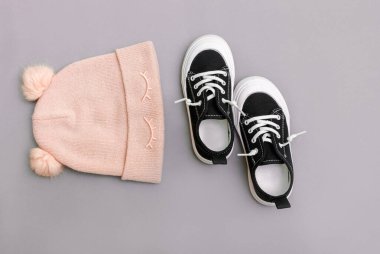 Çocuk kıyafetleri. Gri arka planda cneakers ile örülmüş şapka. Üst Manzara. Moda konsepti. Çocukların sonbahar kıyafetleri.