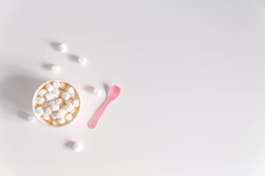 Marşmelov kutuları ve sevimli pembe kaşıkları olan minimalist beyaz arka plan. Tasarım için maket, metin için boşluk, düz yatış