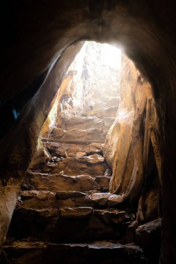 step stone staircase in the ruins of the ancient cave city. Underground river flowing in rock tunnel. Dark creepy abandoned underground chalky cave. Selective focus