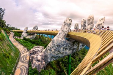 Da Nang, Vietnam - 12 Aug 2022: the Golden Bridge is lifted by two giant hands in the tourist resort on Ba Na Hill in Da Nang, Vietnam. Ba Na mountain resort is a favorite destination for tourists.