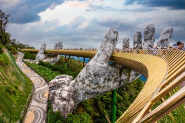 Da Nang, Vietnam - 12 Aug 2022: the Golden Bridge is lifted by two giant hands in the tourist resort on Ba Na Hill in Da Nang, Vietnam. Ba Na mountain resort is a favorite destination for tourists.