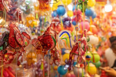 Decorated colorful lanterns hanging on a stand in the streets of Cholon in Ho Chi Minh City, Vietnam during Mid Autumn Festival. Chinese language in photos mean money and happiness. Selective focus.