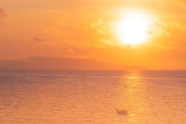 Beautiful cloudscape over the sea, sunrise shot. Lonely boats. Vung Tau beach, Vietnam with beautiful yellow sunrise sky, sun and clouds in orange and blue tones. Background and travel concept.