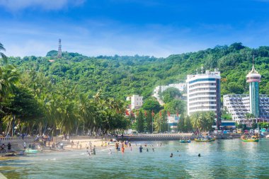 Vung Tau, Vietnam - 24 July 2022: People having rest on beach in Vungtau in sunset light. The Vung Tau city is popular among Ho chi minh city people as sea resort. Landscape and travel concept.