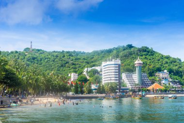 Vung Tau, Vietnam - 24 July 2022: People having rest on beach in Vungtau in sunset light. The Vung Tau city is popular among Ho chi minh city people as sea resort. Landscape and travel concept.