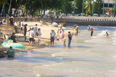 Vung Tau, Vietnam - 24 July 2022: People having rest on beach in Vungtau in sunset light. The Vung Tau city is popular among Ho chi minh city people as sea resort. Landscape and travel concept.