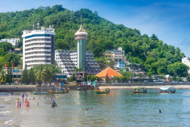 Vung Tau, Vietnam - 24 July 2022: People having rest on beach in Vungtau in sunset light. The Vung Tau city is popular among Ho chi minh city people as sea resort. Landscape and travel concept.