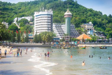 Vung Tau, Vietnam - 24 July 2022: People having rest on beach in Vungtau in sunset light. The Vung Tau city is popular among Ho chi minh city people as sea resort. Landscape and travel concept.