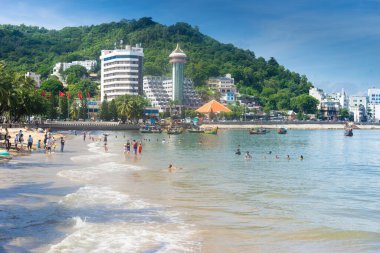 Vung Tau, Vietnam - 24 July 2022: People having rest on beach in Vungtau in sunset light. The Vung Tau city is popular among Ho chi minh city people as sea resort. Landscape and travel concept.