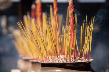 Close up of burning incense sticks on the doors of temples in Vietnam. Burning incense sticks inside a large metal container. Religion concept.