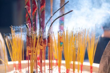Close up of burning incense sticks on the doors of temples in Vietnam. Burning incense sticks inside a large metal container. Religion concept.