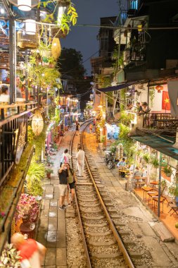 Hanoi, Vietnam - 08 Mayıs 2023: Hanoi Eski Mahallesi 'nin dar bir sokağından geçen tren görüntüsü. Turistler trenin resimlerini çekiyorlar. Hanoi Tren Sokağı popüler bir eğlencedir..
