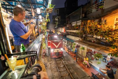 Hanoi, Vietnam - 08 Mayıs 2023: Hanoi Eski Mahallesi 'nin dar bir sokağından geçen tren görüntüsü. Turistler trenin resimlerini çekiyorlar. Hanoi Tren Sokağı popüler bir eğlencedir..