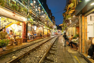 Hanoi, Vietnam - 08 Mayıs 2023: Hanoi Eski Mahallesi 'nin dar bir sokağından geçen tren görüntüsü. Turistler trenin resimlerini çekiyorlar. Hanoi Tren Sokağı popüler bir eğlencedir..