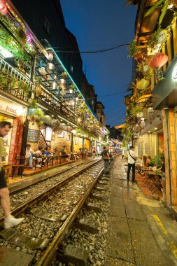 Hanoi, Vietnam - 08 Mayıs 2023: Hanoi Eski Mahallesi 'nin dar bir sokağından geçen tren görüntüsü. Turistler trenin resimlerini çekiyorlar. Hanoi Tren Sokağı popüler bir eğlencedir..