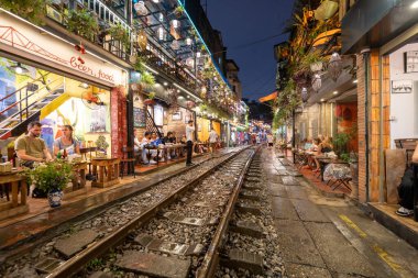 Hanoi, Vietnam - 08 Mayıs 2023: Hanoi Eski Mahallesi 'nin dar bir sokağından geçen tren görüntüsü. Turistler trenin resimlerini çekiyorlar. Hanoi Tren Sokağı popüler bir eğlencedir..