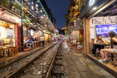 Hanoi, Vietnam - 08 Mayıs 2023: Hanoi Eski Mahallesi 'nin dar bir sokağından geçen tren görüntüsü. Turistler trenin resimlerini çekiyorlar. Hanoi Tren Sokağı popüler bir eğlencedir..