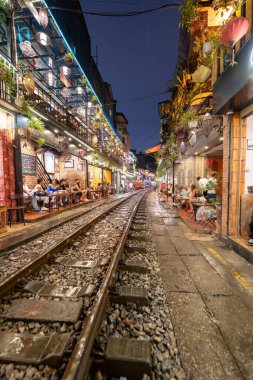 Hanoi, Vietnam - 08 Mayıs 2023: Hanoi Eski Mahallesi 'nin dar bir sokağından geçen tren görüntüsü. Turistler trenin resimlerini çekiyorlar. Hanoi Tren Sokağı popüler bir eğlencedir..