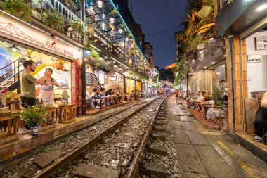Hanoi, Vietnam - 08 Mayıs 2023: Hanoi Eski Mahallesi 'nin dar bir sokağından geçen tren görüntüsü. Turistler trenin resimlerini çekiyorlar. Hanoi Tren Sokağı popüler bir eğlencedir..