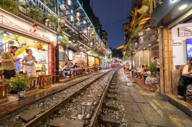 Hanoi, Vietnam - 08 Mayıs 2023: Hanoi Eski Mahallesi 'nin dar bir sokağından geçen tren görüntüsü. Turistler trenin resimlerini çekiyorlar. Hanoi Tren Sokağı popüler bir eğlencedir..
