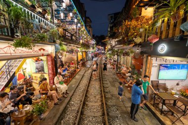 Hanoi, Vietnam - 08 Mayıs 2023: Hanoi Eski Mahallesi 'nin dar bir sokağından geçen tren görüntüsü. Turistler trenin resimlerini çekiyorlar. Hanoi Tren Sokağı popüler bir eğlencedir..