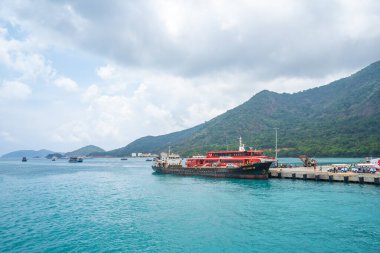 Con Dao Adası, Vietnam - 30 Nisan 2023: Vung Tau şehrinden Con Dao adasındaki Ben Dam limanına giden güzel mavi deniz, mavi gökyüzü dağı ve renkli teknelerin görüntüsü.