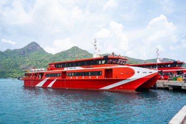 Con Dao Adası, Vietnam - 30 Nisan 2023: Vung Tau şehrinden Con Dao adasındaki Ben Dam limanına giden güzel mavi deniz, mavi gökyüzü dağı ve renkli teknelerin görüntüsü.