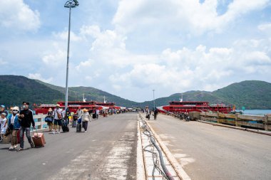 Con Dao Adası, Vietnam - 30 Nisan 2023: Vung Tau şehrinden Con Dao adasındaki Ben Dam limanına giden güzel mavi deniz, mavi gökyüzü dağı ve renkli teknelerin görüntüsü.