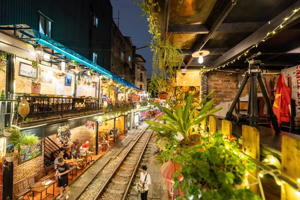 stock image Hanoi, Vietnam - 08 May 2023 : View of train passing through a narrow street of the Hanoi Old Quarter. Tourists taking pictures of hurtling train. The Hanoi Train Street is a popular attraction.