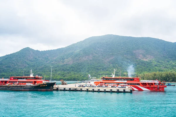 Con Dao Adası, Vietnam - 30 Nisan 2023: Vung Tau şehrinden Con Dao adasındaki Ben Dam limanına giden güzel mavi deniz, mavi gökyüzü dağı ve renkli teknelerin görüntüsü.