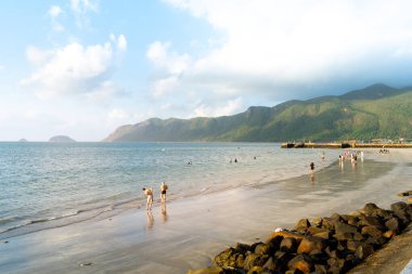 Con Dao Adası, Vietnam - 01 Mayıs 2023: Ünlü Con Dao sahilinde deniz dalgalarının tadını çıkaran turistler. Seyahat ve manzara konsepti.