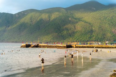 Con Dao Adası, Vietnam - 01 Mayıs 2023: Ünlü Con Dao sahilinde deniz dalgalarının tadını çıkaran turistler. Seyahat ve manzara konsepti.