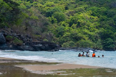 Con Dao Adası, Vietnam - 01 Mayıs 2023: Con Dao Adası, Vietnam 'daki Güzel Baraj Trau Sahili. Dalgalı kıyı manzarası, açık gökyüzü ve yol, mavi deniz, turistler ve dağ.