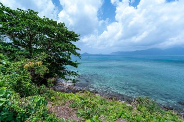 Vietnam 'da barış dolu bir Con Dao adası Vietnam' ın cennet adasıdır. Dalgalı kıyı manzarası, kıyı şeridi, açık gökyüzü ve yol, mavi deniz, turistler ve dağ. Seyahat ve manzara konsepti.