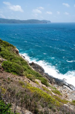 Vietnam 'da barış dolu bir Con Dao adası Vietnam' ın cennet adasıdır. Dalgalı kıyı manzarası, kıyı şeridi, açık gökyüzü ve yol, mavi deniz, turistler ve dağ. Seyahat ve manzara konsepti.