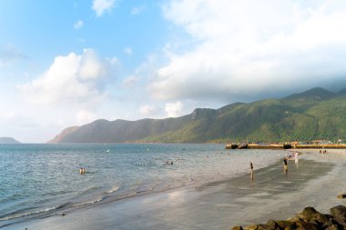 Vietnam 'da barış dolu bir Con Dao adası Vietnam' ın cennet adasıdır. Dalgalı kıyı manzarası, kıyı şeridi, açık gökyüzü ve yol, mavi deniz, turistler ve dağ. Seyahat ve manzara konsepti.