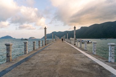 Con Son kasabasındaki yeni Con Dao yolcu limanının manzarası. Huzurlu bir Con Dao Adası, Vietnam. Dalgalı kıyı manzarası, kıyı şeridi, açık gökyüzü, mavi deniz, turistler ve dağ. Seyahat ve manzara konsepti.
