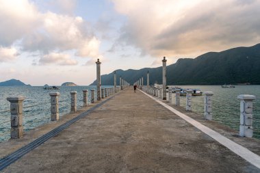 Con Son kasabasındaki yeni Con Dao yolcu limanının manzarası. Huzurlu bir Con Dao Adası, Vietnam. Dalgalı kıyı manzarası, kıyı şeridi, açık gökyüzü, mavi deniz, turistler ve dağ. Seyahat ve manzara konsepti.
